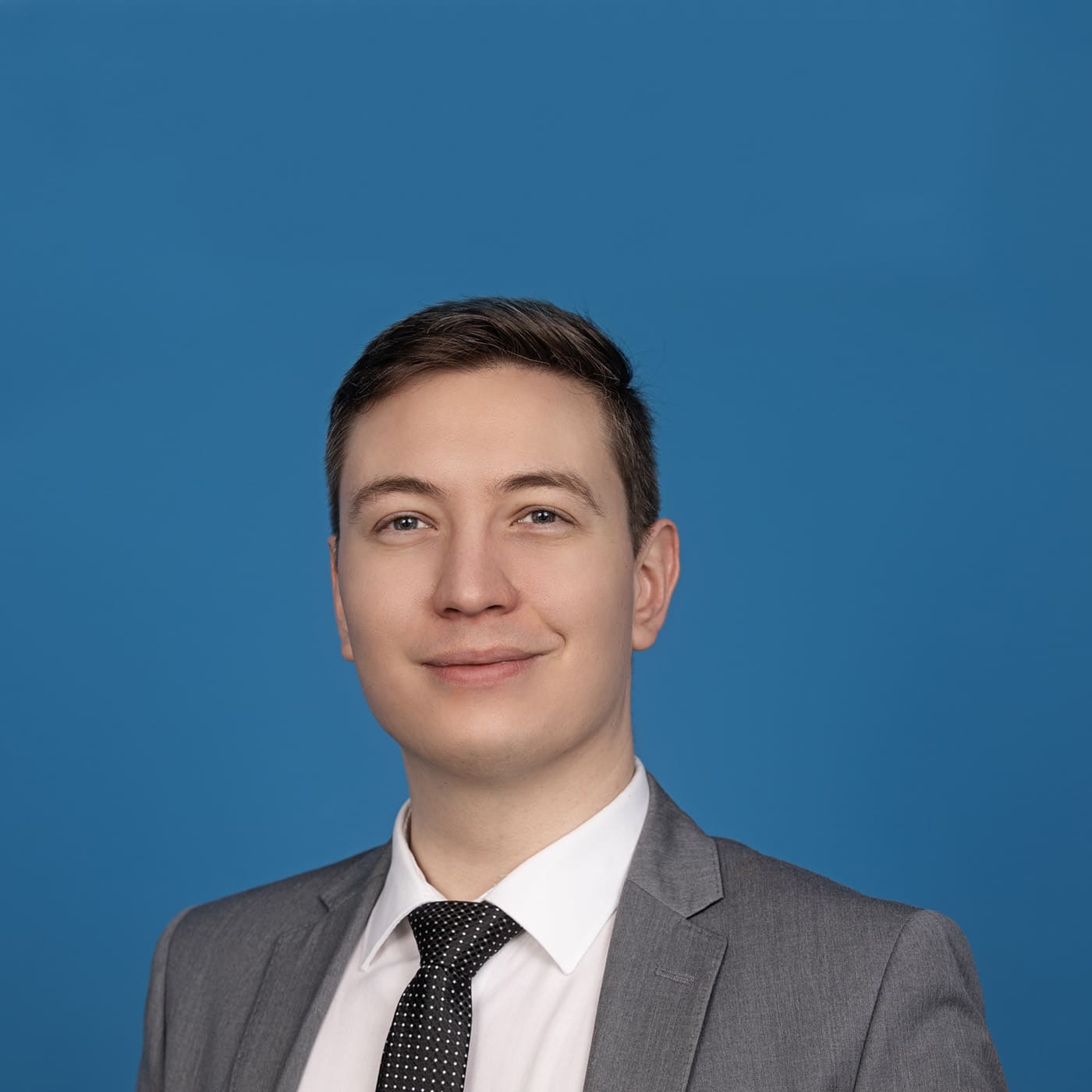 Young man looking into the camera in front of blue background.