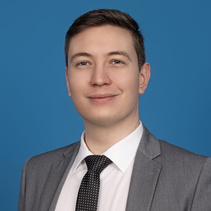 Young man looking into the camera in front of blue background.