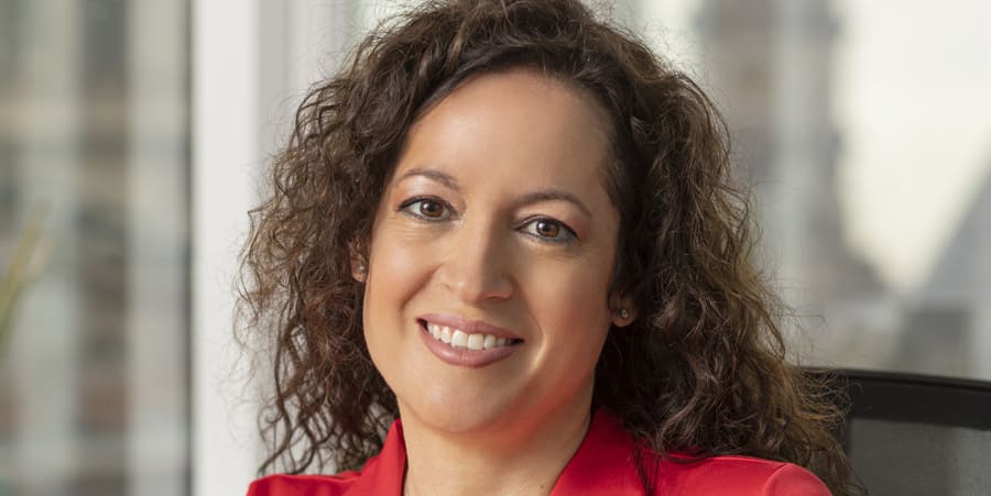 Woman with curly hair in red dress smiling into the camera